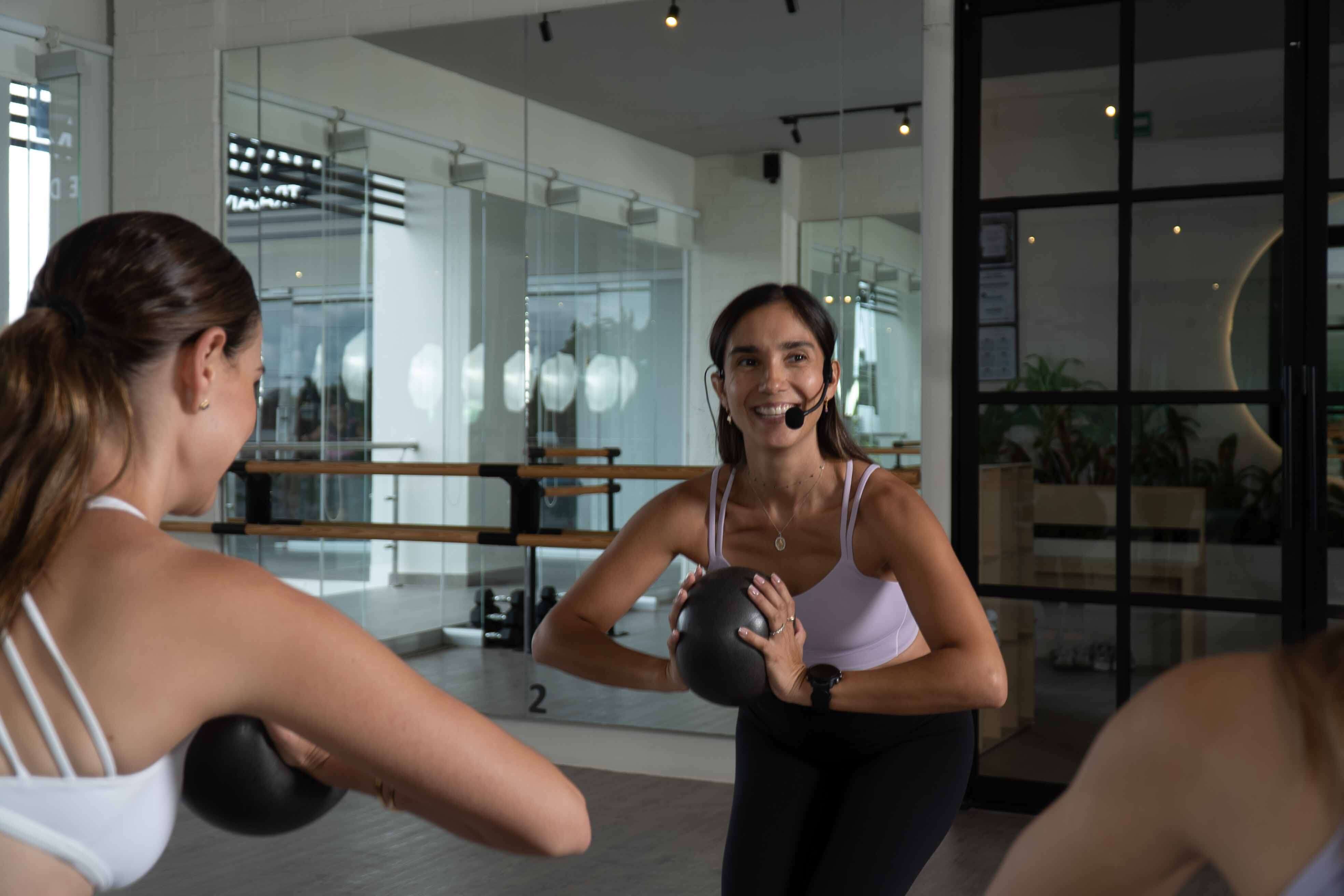 Una coach de OME sonriendo con una pelota durante la clase